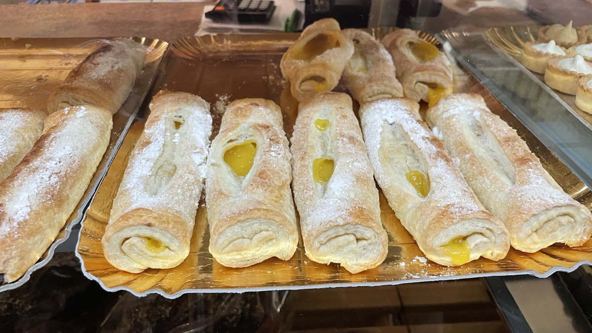 Cannoncini di pasta sfoglia ripieni di crema, spolverati di zucchero a velo